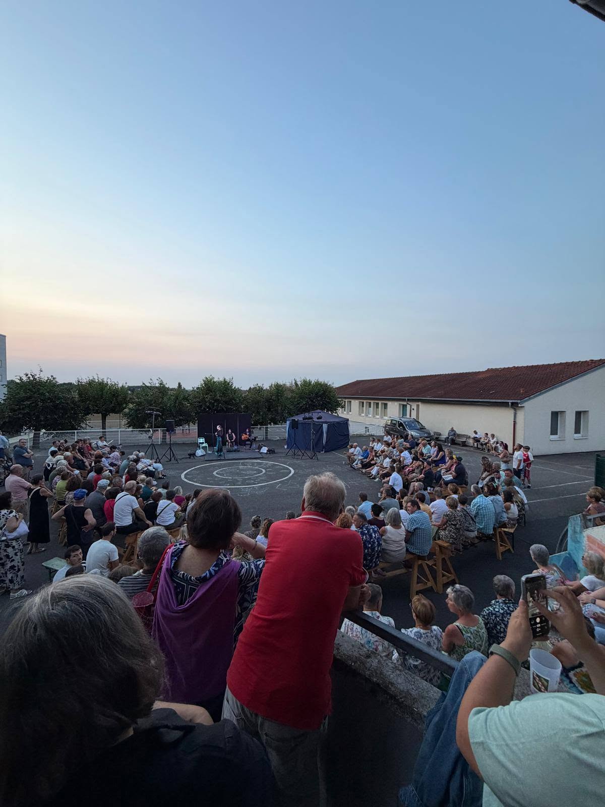 The audience seated outdoors around the stage of the Herencia show, at the foyer rural in Holving